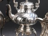 trois théières en argent et une théière en argent posée sur un support