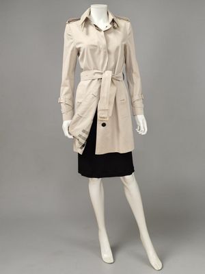 a mannequin wearing a beige trench coat and black skirt