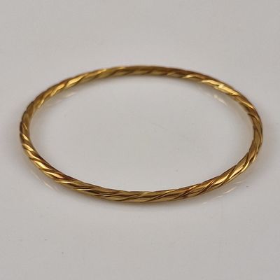 a close up of a gold bracelet on a white surface