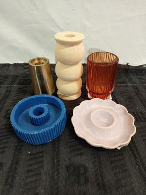 four different colored vases and a candle holder on a table