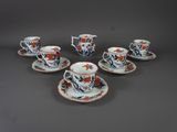 six tasses et soucoupes ornées de fleurs orange, posées sur une table