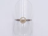 an image of a white pearl and diamond ring on a clear glass