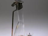 une carafe en verre munie d'une poignée en métal, à côté d'un verre