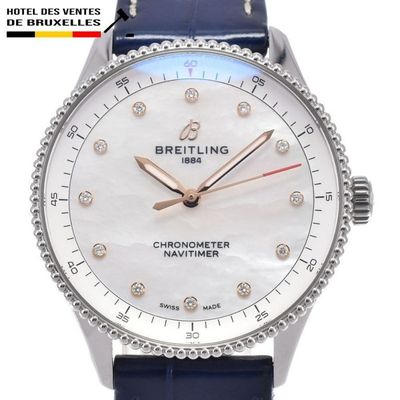 La montre est blanche, avec un bracelet bleu et un cadran orné d'une lunette sertie de diamants.
