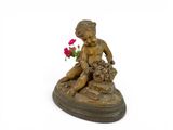 a statue of a boy sitting on a rock with a flower in his hand