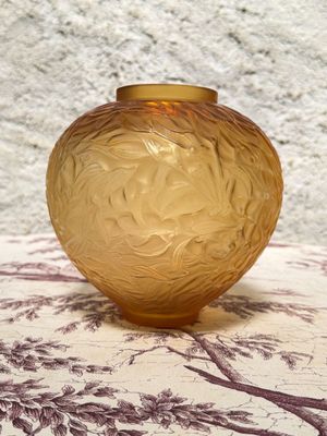 a yellow glass vase sitting on a table with a purple and white table cloth