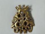 a close up of a gold brooch with a bird on it