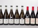six bottles of wine lined up in a row on a white surface