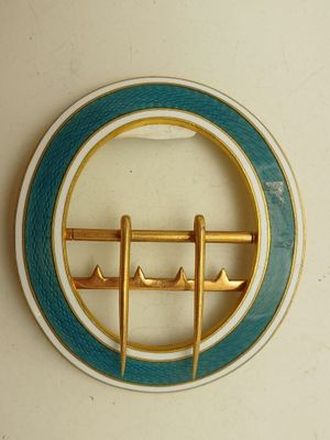 une broche bleue et dorée sur laquelle est représenté un bateau