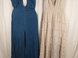 two women ' s dresses hanging on a clothes rack in front of a white backdrop