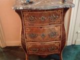 a marble top chest of drawers in the corner of a room