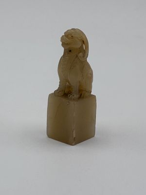 une statue représentant un chien assis sur un bloc de bois