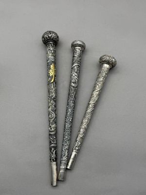 trois stylos en métal de couleur argent posés les uns à côté des autres sur une table