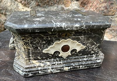 une boîte en marbre posée sur une table, avec un mur en pierre en arrière-plan