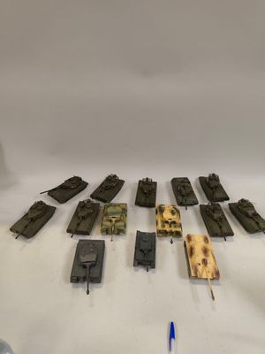 un ensemble de véhicules militaires miniatures et un petit pistolet miniature posés sur une surface blanche