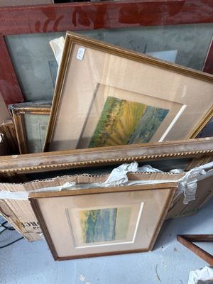 une pile d'œuvres d'art encadrées posées par terre dans une pièce