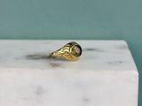 un gros plan d'une bague en or sertie d'une tourmaline verte