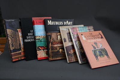 Plusieurs livres sont alignés sur une table devant un fond noir.