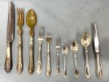 a lot of silverware on a table with a knife, fork, spoon, and spoon rest