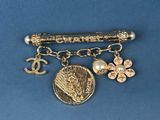 a gold brooch with charms on it on a blue surface