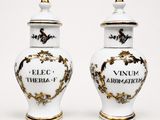 pair of white and gold vases with writing on them on a white surface