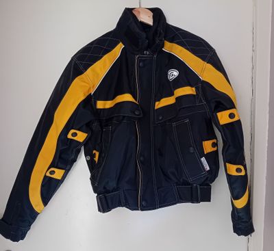 une veste de moto jaune et noire accrochée au mur devant une porte blanche