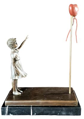 a statue of a girl with a balloon on a stand