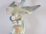 a figurine of a bird and two birds sitting on a branch