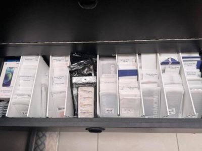 un tiroir rempli d'appareils électroniques posé sur un sol carrelé