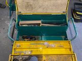 une boîte à outils jaune posée par terre, contenant des outils