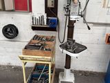 une perceuse à colonne dans un atelier, avec des outils posés sur la table