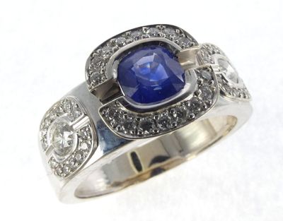 a close up of a ring with a blue stone surrounded by diamonds