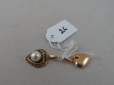 a gold charm with a pearl and a tag on it