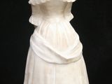 a white statue of a woman in a dress on a black background