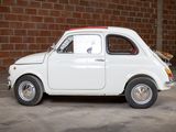a small white car parked in front of a brick wall