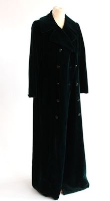 un long manteau noir posé sur un mannequin, sur fond blanc