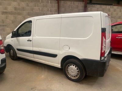 une camionnette blanche garée sur un parking à côté d'une voiture rouge