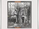 black and white photograph of a man standing in front of a house