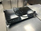 une plaque de cuisson noire surmontée d'un brûleur noir