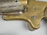 a brass revolver with a wooden handle on a white surface
