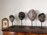 five wooden masks on display on a wooden table
