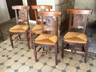 four wooden chairs sitting next to each other on a tiled floor