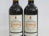 two bottles of red wine sitting next to each other on a white surface