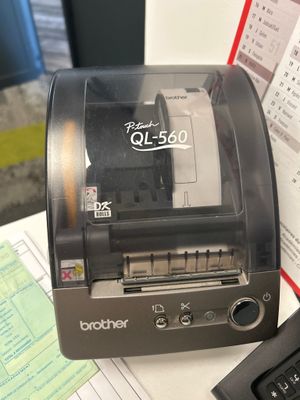 une photo d'une imprimante Brother QL-240 posée sur un bureau à côté d'un clavier