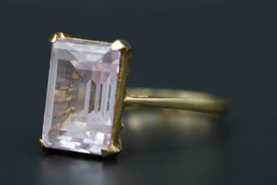 un gros plan d'une bague ornée d'une pierre rose sur un fond noir