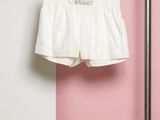 un short blanc suspendu à un portant contre un mur rose et blanc