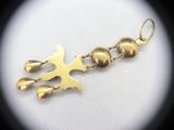 a gold charm with a bird on it on a white surface