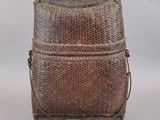 une photo représentant un sac tissé marron posé sur un support en bois