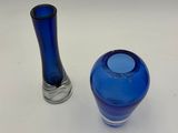 pair of blue glass vases sitting on a white surface