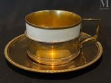 a gold cup and saucer sitting on a black table